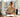 Smiling businesswoman enjoying a peaceful break at a sunny wooden desk by a window.