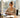 Smiling businesswoman enjoying a peaceful break at a sunny wooden desk by a window.